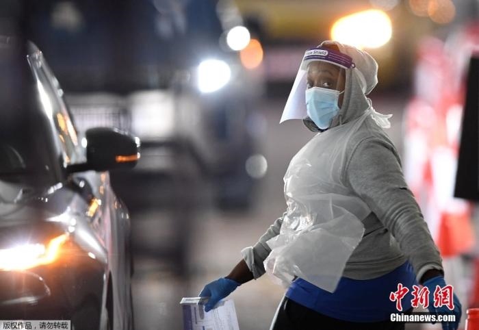 當(dāng)?shù)貢r間12月18日，英國政府公布的數(shù)據(jù)顯示，當(dāng)天英國新增奧密克戎毒株感染病例10059例。鑒于奧密克戎毒株感染病例激增，住院人數(shù)不斷上升，倫敦市長宣布倫敦進(jìn)入“重大事故”狀態(tài)。圖為倫敦的一個免下車檢測中心，一名醫(yī)務(wù)工作者正準(zhǔn)備對司機進(jìn)行核酸檢測。