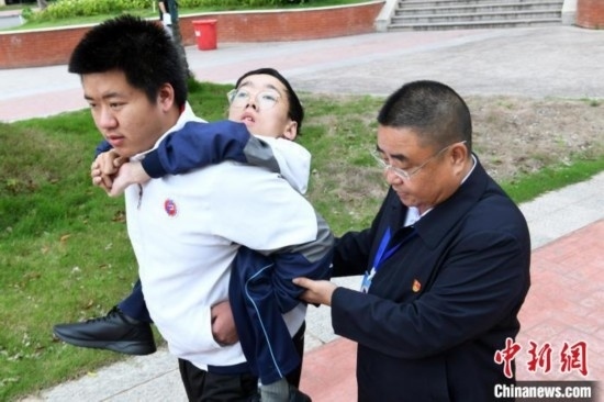 朱金祥背著鐘華強(qiáng)去教室上課的路上，也經(jīng)常碰到值班的校領(lǐng)導(dǎo)和老師前來搭把手。 卓忠偉 攝