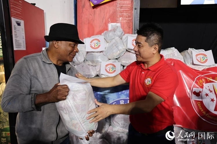 巴西中國浙江商會會長鄭俠茂向社區(qū)居民轉(zhuǎn)交捐贈物資。人民網(wǎng)記者 時(shí)元皓攝