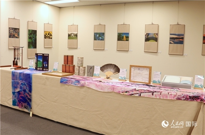 現(xiàn)場展出的馮學(xué)敏攝影作品與湖州市特色工藝品。（人民網(wǎng) 許可攝）