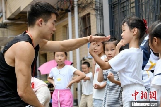 圖為大學生志愿者在組織孩子們參加體育健身活動。廖光福 攝