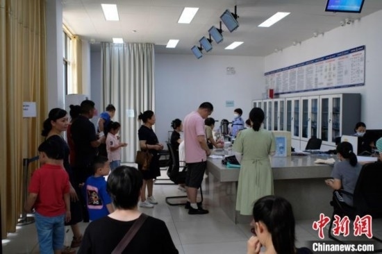 圖為在戶籍辦證廳內(nèi)排隊等待的家長和孩子。劉俊聰 攝
