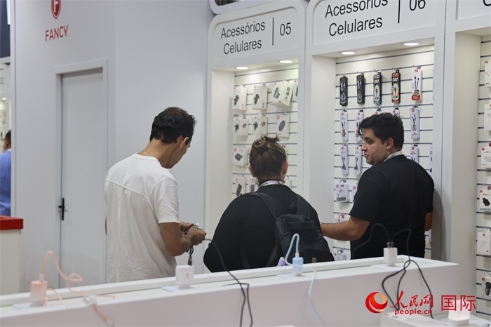 幾名參觀者在一個展臺前了解手機(jī)配件。（人民網(wǎng)記者 時元皓攝）