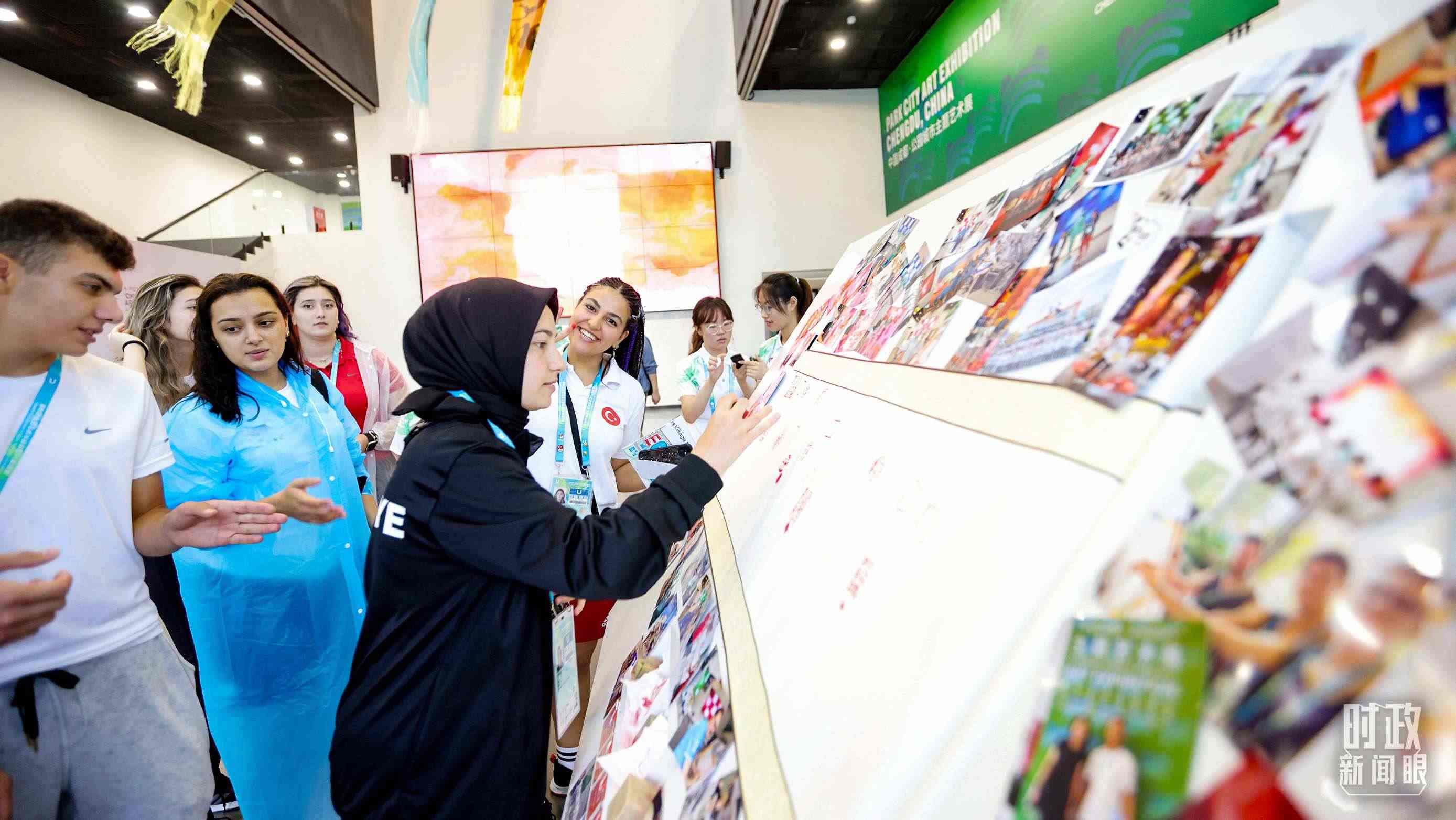 各國青年運(yùn)動(dòng)員正在參觀成都大運(yùn)村內(nèi)的“雪山下的公園城市，煙火里的幸福成都”主題藝術(shù)展。（總臺(tái)央視記者魏幫軍拍攝）