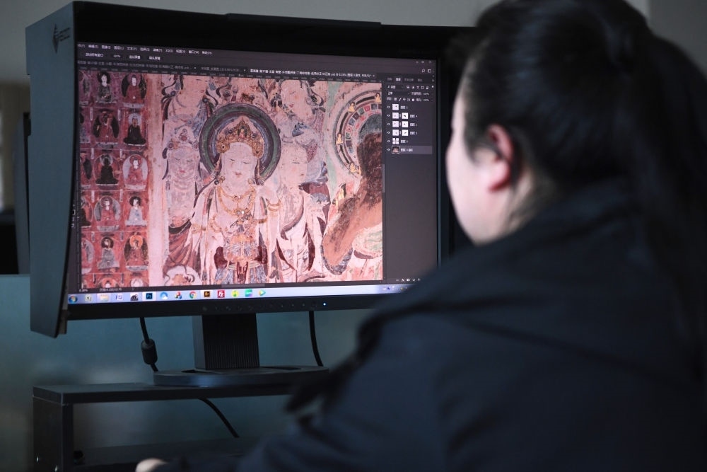 敦煌研究院文物數(shù)字化保護(hù)團(tuán)隊圖像處理人員年海麗在拼接壁畫圖像（2023年4月25日攝）。數(shù)字化探索為莫高窟的保護(hù)與傳承開辟了全新路徑，數(shù)字技術(shù)讓敦煌文物走出洞窟，跨出國門，走向“永久保存、永續(xù)利用”。新華社記者 陳斌 攝