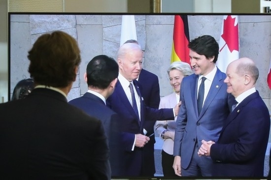 2022年3月24日，在比利時布魯塞爾的北約總部，一名男子觀看屏幕上美國總統(tǒng)拜登（右四）、歐盟委員會主席馮德萊恩（右三）、加拿大總理特魯多（右二）、德國總理朔爾茨（右一）出席七國集團峰會合影儀式的畫面。新華社記者鄭煥松攝