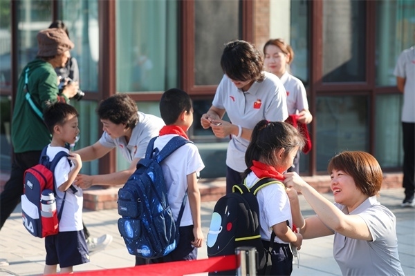 8月30日，雄安史家胡同小學(xué)學(xué)生體驗(yàn)學(xué)校生活。老師為學(xué)生佩戴校徽。