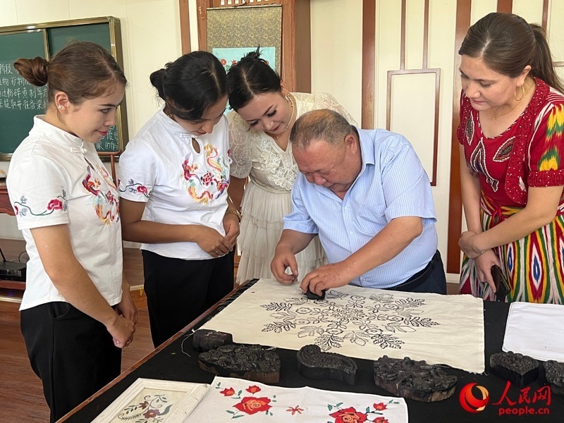 國家級非物質(zhì)文化遺產(chǎn)模戳印花布技藝傳承人吾吉阿西木?吾舒爾展示模戳印花布的制作過程。人民網(wǎng)記者 常雪梅攝