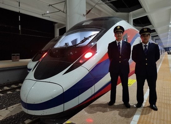 劉銀能（右一）與中國(guó)師父鄔俊鴻在動(dòng)車組前合影。受訪者供圖