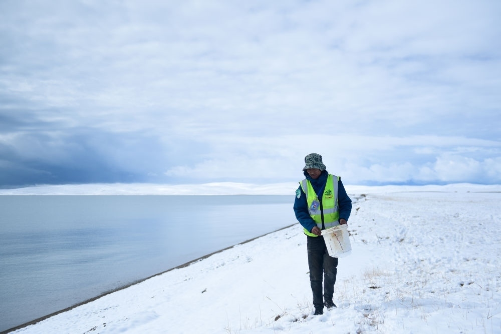 2021年10月20日，在青海省果洛藏族自治州瑪多縣扎陵湖鄉(xiāng)勒那村，三江源國家公園黃河源園區(qū)生態(tài)管護(hù)員在扎陵湖邊撿拾垃圾。新華社記者 張龍 攝