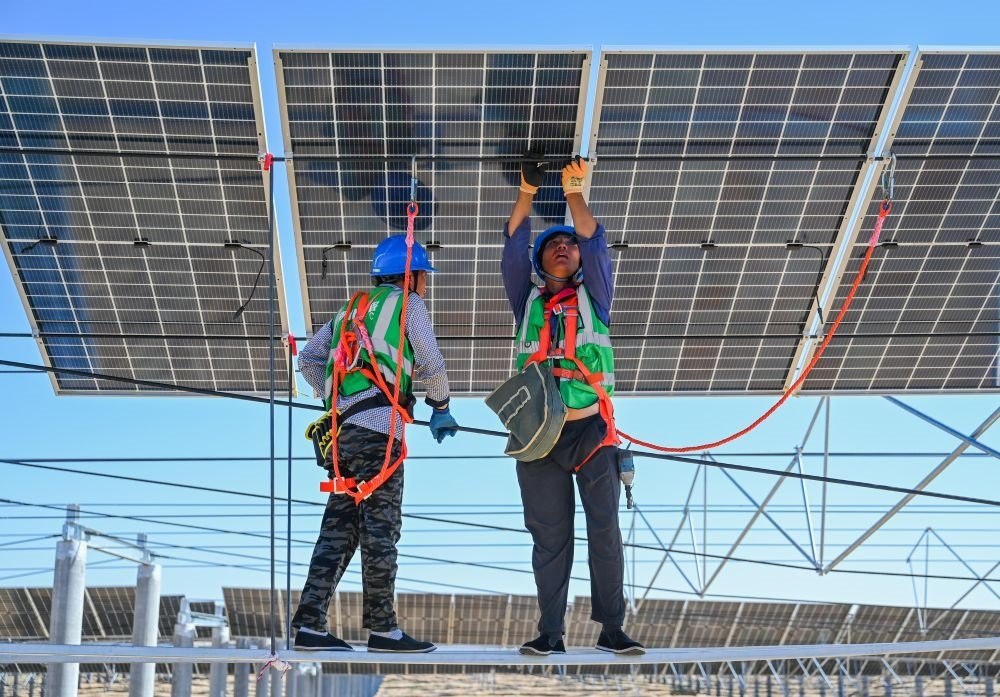 2023年7月22日，工人在位于內(nèi)蒙古杭錦旗庫布其沙漠億利生態(tài)示范區(qū)的蒙西基地庫布其200萬千瓦光伏治沙項目工地安裝光伏板。新華社記者 劉磊 攝