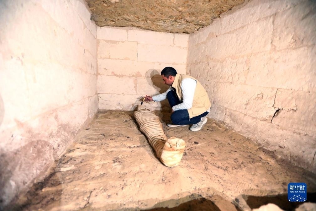 10月15日，在埃及明亞省考古現(xiàn)場(chǎng)，考古人員清理一座石鑿墓中的木乃伊。新華社發(fā)（艾哈邁德·戈馬攝）