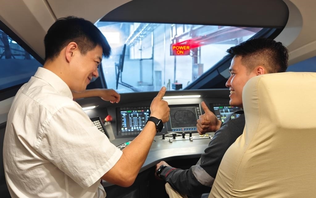 8月25日，在印度尼西亞萬隆的雅萬高鐵德卡魯爾動車所內(nèi)，中國師傅穆振（左）在向印尼火車司機塞蒂亞萬講解動車組出庫前的上電作業(yè)。