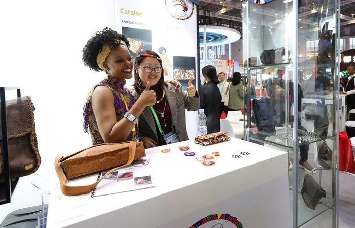 11月6日，一位參觀者（右）在第六屆進(jìn)博會(huì)國(guó)家展南非展臺(tái)試戴傳統(tǒng)首飾。