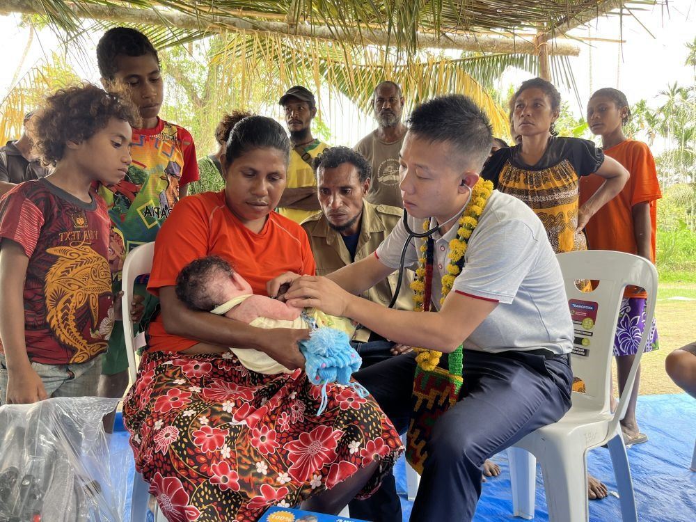 2023年8月5日，在巴布亞新幾內(nèi)亞中央省的一個(gè)村莊里，第12批援巴新中國(guó)醫(yī)療隊(duì)副隊(duì)長(zhǎng)、新生兒科副主任醫(yī)師劉振球?yàn)閶雰禾仿犜\檢查。泰樂出生時(shí)患有重癥，一度生命垂危，經(jīng)過劉振球與當(dāng)?shù)蒯t(yī)護(hù)人員的救治最終痊愈。從2002年起，中國(guó)連續(xù)向巴新派出12批醫(yī)療隊(duì)，為提高巴新醫(yī)療衛(wèi)生水平作出積極貢獻(xiàn)。