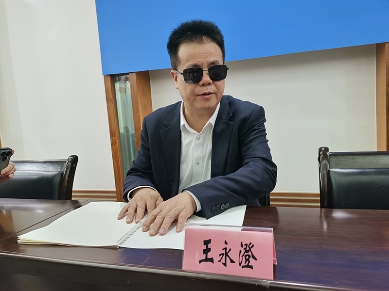 全國(guó)人大代表王永澄正在閱讀盲文版代表建議答復(fù)。本報(bào)記者 張 璁?dāng)z