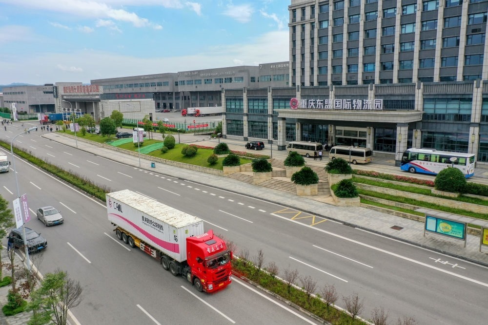 2023年10月11日，滿載筆記本電腦配件、發(fā)電機組件等產(chǎn)品的西部陸海新通道跨境公路班車從重慶南彭公路保稅物流中心駛出，將途經(jīng)廣西憑祥，直達越南（無人機照片）。新華社記者 黃偉 攝