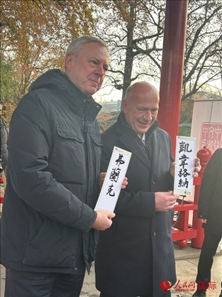 柏林市長韋格納（右）、動物園監(jiān)事會主席布魯克曼（左）手持中國文化中心工作人員現(xiàn)場手書的中文名字。人民網(wǎng)記者 徐馨攝