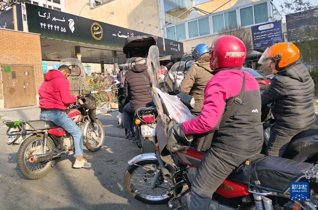 12月18日，摩托車在伊朗首都德黑蘭的一家加油站外等待加油。新華社記者 沙達提 攝