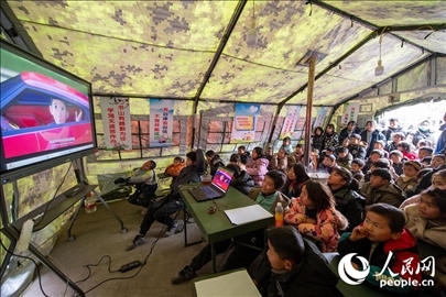 12月22日，在積石山縣大河家鎮(zhèn)大河村安置點，陸軍76集團軍某旅搭建的“臨時學(xué)?！眱?nèi)，小朋友正在看動畫片。人民網(wǎng)記者 翁奇羽攝