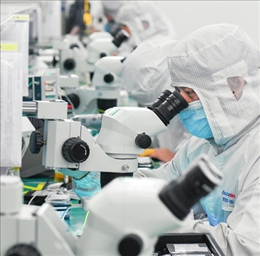 在位于武漢中國光谷的光電器件研發(fā)制造商——武漢光迅科技股份有限公司生產(chǎn)車間內(nèi)，技術(shù)人員在光模塊生產(chǎn)線作業(yè)（2023年4月11日攝）。程敏攝/本刊