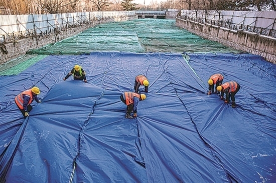 1月3日，房山區(qū)東風街道，工人正在修復的河道內給混凝土鋪設保溫布。