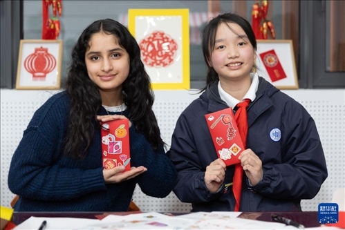 1月28日，美國馬斯卡廷中學(xué)學(xué)生（左）和復(fù)旦大學(xué)第二附屬學(xué)校學(xué)生展示互相送出的寫有寄語祝福的紅包。 新華社記者 王翔 攝