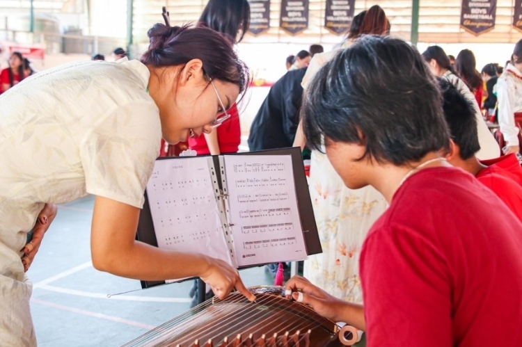 志愿者教師指導(dǎo)學(xué)生彈奏古箏。活動(dòng)主辦方供圖