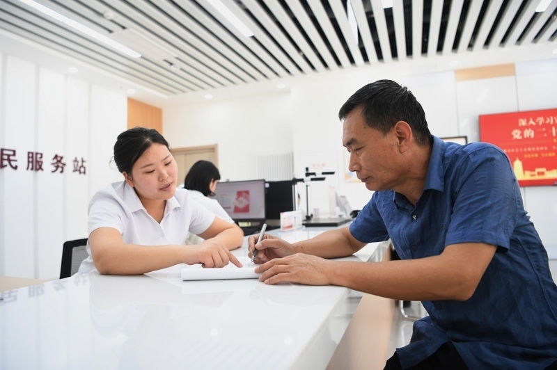 2023年5月23日，河北雄安新區(qū)容東片區(qū)南文營社區(qū)居民（右）在社區(qū)便民服務站辦理業(yè)務。