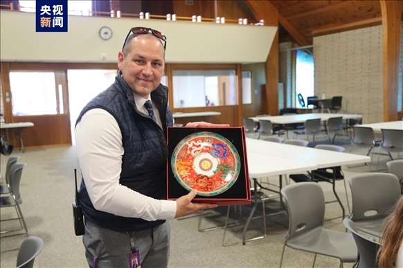 △馬斯卡廷中學(xué)高中部校長瑞安·卡斯?fàn)柎韺W(xué)校接受總臺文創(chuàng)產(chǎn)品