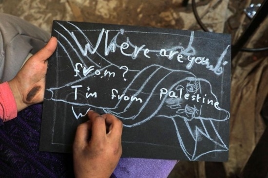 2023年12月28日，一名學(xué)生在加沙地帶南部城市拉法一所學(xué)校的臨時(shí)教室中寫下“我來(lái)自巴勒斯坦”的字樣。新華社發(fā)（里澤克·阿卜杜勒賈瓦德攝）