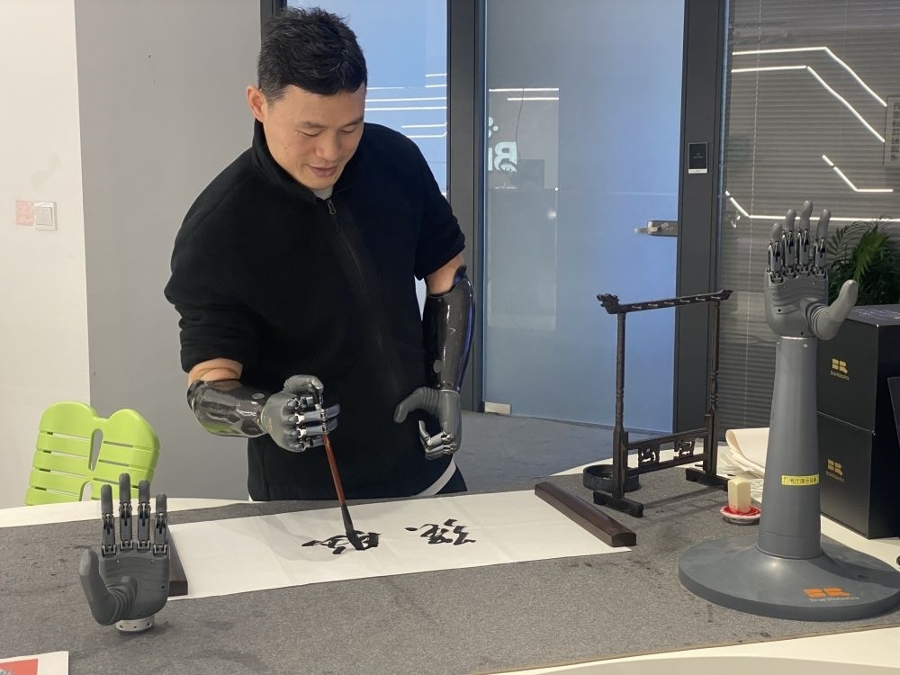 2024年3月29日，在浙江強(qiáng)腦科技有限公司展廳內(nèi)，失去雙手的產(chǎn)品體驗(yàn)官倪敏成依靠智能仿生手寫毛筆字。新華社記者 魏一駿 攝