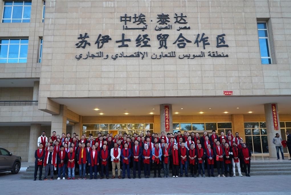 2024年2月11日，在位于埃及蘇伊士省的中?！ぬ┻_(dá)蘇伊士經(jīng)貿(mào)合作區(qū)，中埃員工在合作區(qū)辦公大樓前合影拜年。新華社發(fā)（泰達(dá)合作區(qū)供圖）