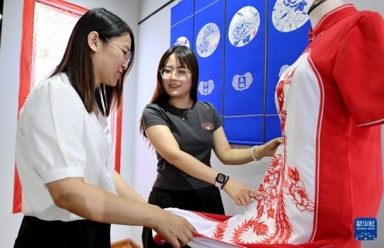 5月31日，在衡水市阜城縣一家剪紙工作室，游客在觀賞帶有剪紙?jiān)氐钠炫邸? width=