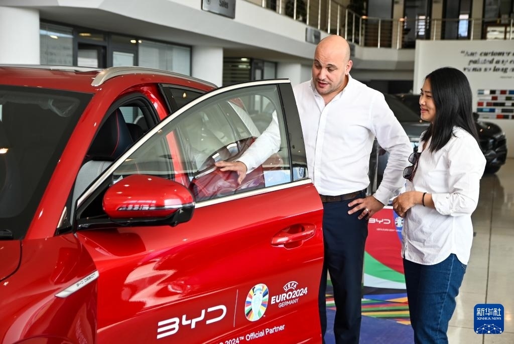 2024年5月29日，在馬耳他比爾基卡拉，馬耳他哈桑-扎米特汽車公司首席執(zhí)行官德古阿拉（左）介紹一輛比亞迪純電動汽車。新華社發(fā)（喬納森·博格 攝）