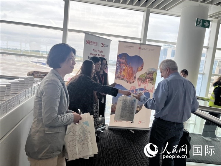 圖為工作人員向乘客發(fā)放復(fù)航首班禮物。 牛瑞飛攝