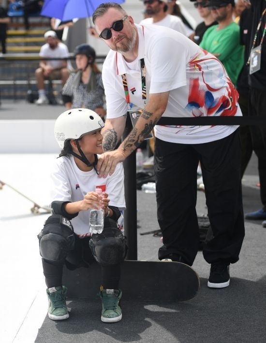 6月20日，鄭好好（左）在比賽間隙與教練互動，她在預賽中最佳成績?yōu)?2.60分。當日，巴黎奧運會資格系列賽布達佩斯站滑板女子碗池預賽在布達佩斯舉行。新華社記者 賀燦鈴 攝