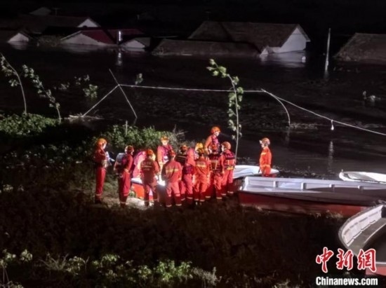  7月6日凌晨3時(shí)，在湖南岳陽(yáng)華容縣團(tuán)洲垸洞庭湖一線堤防，救援人員剛剛完成一次救援任務(wù)，遠(yuǎn)處是被淹的民房。中新社記者 白祖偕 攝