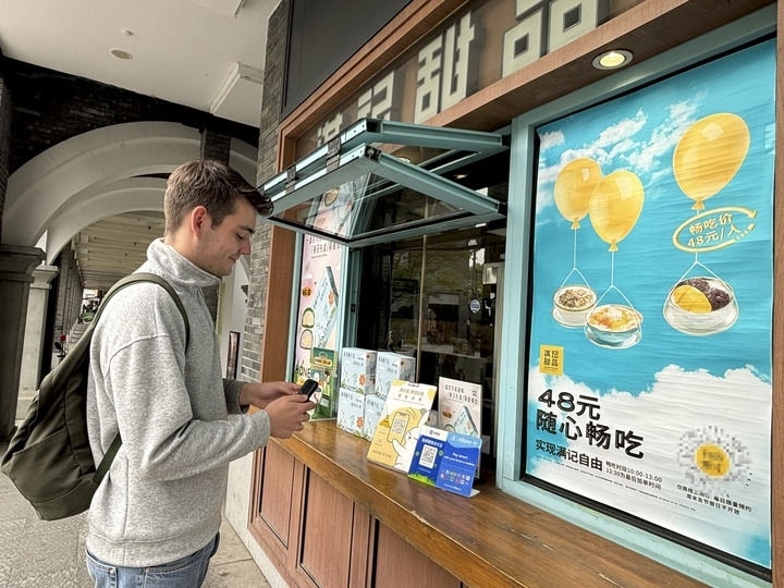 來自德國的留學(xué)生理查德在杭州西湖邊一家商鋪使用支付寶掃碼支付（2024年4月11日攝）。新華社發(fā)