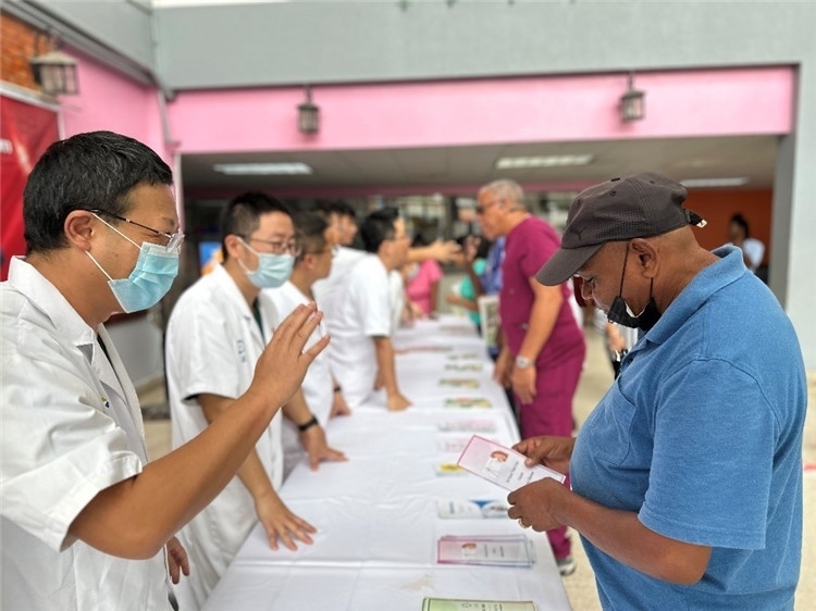 援圭醫(yī)療隊隊員們在啟動儀式上為當(dāng)?shù)孛癖姺职l(fā)宣傳手冊。中國援助圭亞那醫(yī)療隊供圖