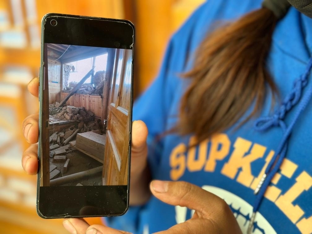 圖為7月17日拉毛東智在手機上找出地震后房屋受損的照片。新華社記者 張子琪 攝