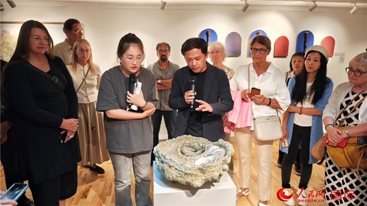 參展人、景德鎮(zhèn)陶瓷大學(xué)設(shè)計(jì)藝術(shù)學(xué)院副院長(zhǎng)余劍峰（中）向來賓介紹參展作品。人民網(wǎng)記者 殷淼攝