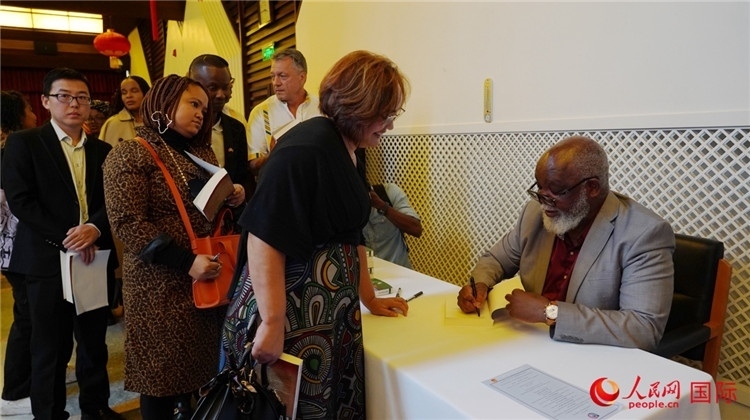 譚哲理在活動(dòng)現(xiàn)場(chǎng)簽名贈(zèng)書。人民網(wǎng) 劉暢攝