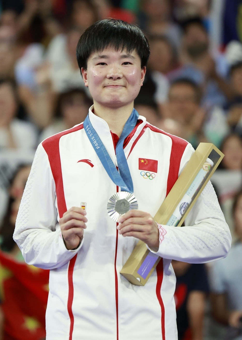 巴黎奧運會羽毛球女子單打亞軍、中國選手何冰嬌在頒獎儀式上一手握著銀牌，一手握著西班牙奧委會徽章（2024年8月5日攝）。新華社記者 任正來 攝