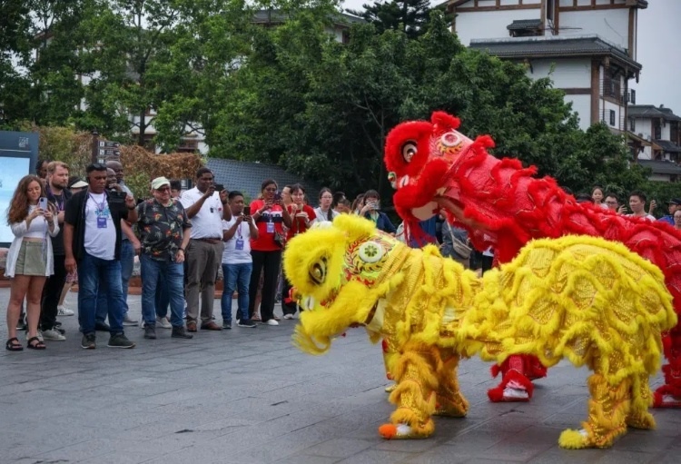 2024“一帶一路”媒體合作論壇聯(lián)合采訪調(diào)研行成員在樂(lè)山蘇稽古鎮(zhèn)觀看非遺舞獅表演。本報(bào)記者 伊霄攝