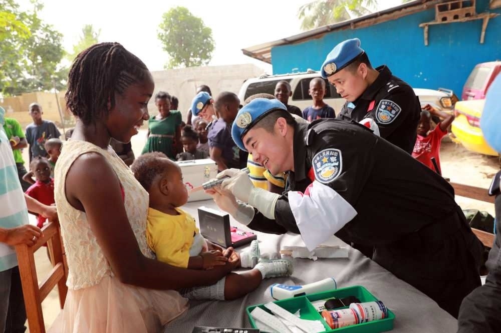 2017年12月28日，在利比里亞蒙羅維亞，中國維和警察防暴隊(duì)醫(yī)療人員為兒童做口腔檢查。