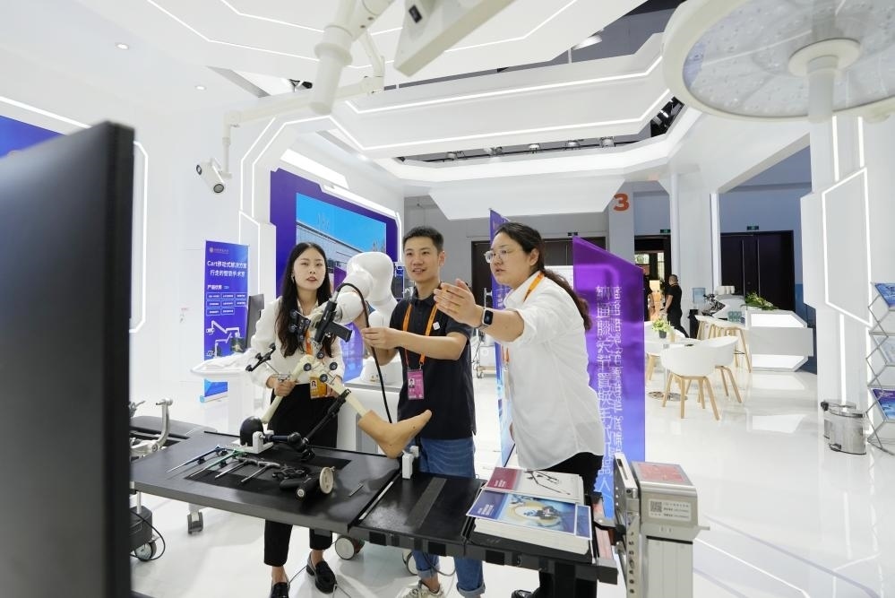 9月11日，一位媒體記者（中）在2024年服貿(mào)會國家會議中心會場體驗北京納通科技集團有限公司的膝關(guān)節(jié)置換手術(shù)機器人。新華社記者鞠煥宗 攝