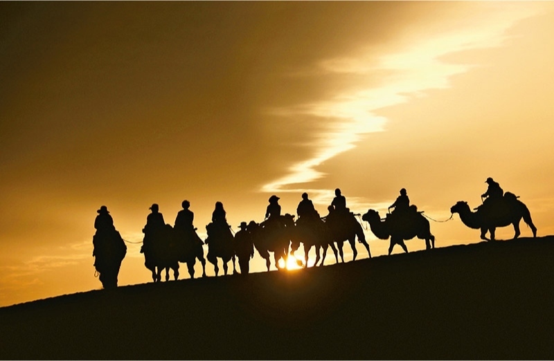 新時(shí)代以來，文化和旅游深度融合發(fā)展體制機(jī)制不斷健全，成功走出了一條獨(dú)具特色的中國旅游發(fā)展之路。圖為2024年9月1日清晨，游客在甘肅省敦煌市鳴沙山月牙泉景區(qū)乘騎駱駝，欣賞大漠風(fēng)光，體驗(yàn)絲路風(fēng)情。 新華社發(fā) 張曉亮/攝