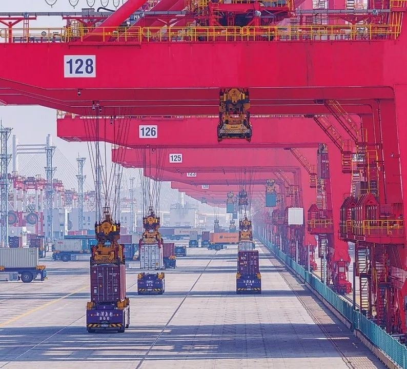 共建“一帶一路”國家在工作制度對接、技術(shù)標(biāo)準(zhǔn)協(xié)調(diào)、檢驗結(jié)果互認等方面強化合作、統(tǒng)一標(biāo)準(zhǔn)，貿(mào)易自由化便利化水平不斷提升。上海洋山港海關(guān)對接共建國家進出口貨物相關(guān)標(biāo)準(zhǔn)，推動通關(guān)一體化方式申報，提升通關(guān)效率。圖為無人駕駛的全自動導(dǎo)引車在洋山港穿梭往來，搬運集裝箱。王初 攝