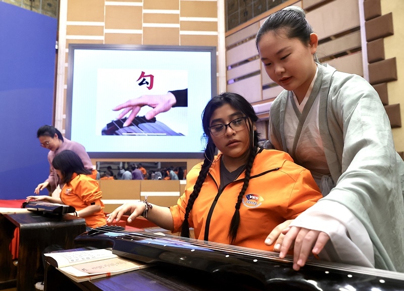 2024年3月20日，美國華盛頓州中學(xué)生代表團北京大學(xué)交流活動在北京大學(xué)英杰交流中心舉行。圖為來自華盛頓州的中學(xué)生體驗古琴。